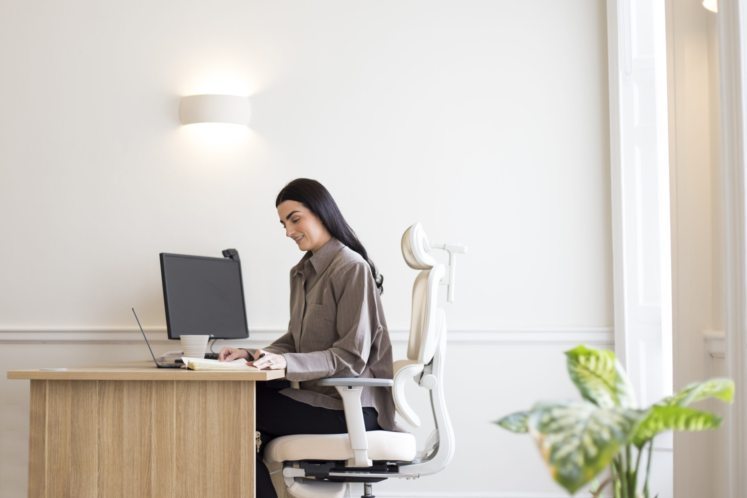 Therapist sat at desk with green plant in corner